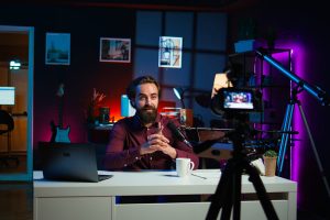 Happy internet star using professional recording equipment to film vlog channel intro for online streaming platforms, arriving in studio. Joyful man greets fans, presenting today video topic, camera B